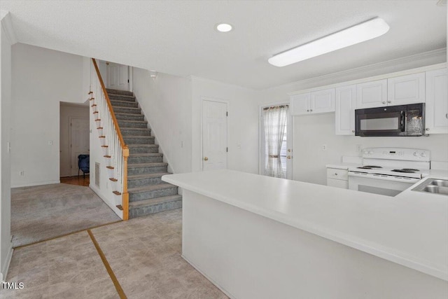 kitchen featuring a peninsula, light countertops, black microwave, white cabinetry, and white range with electric stovetop