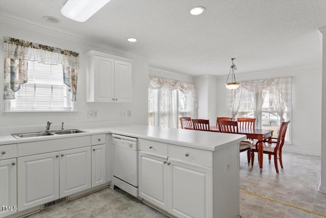 kitchen featuring visible vents, a sink, a peninsula, light countertops, and dishwasher