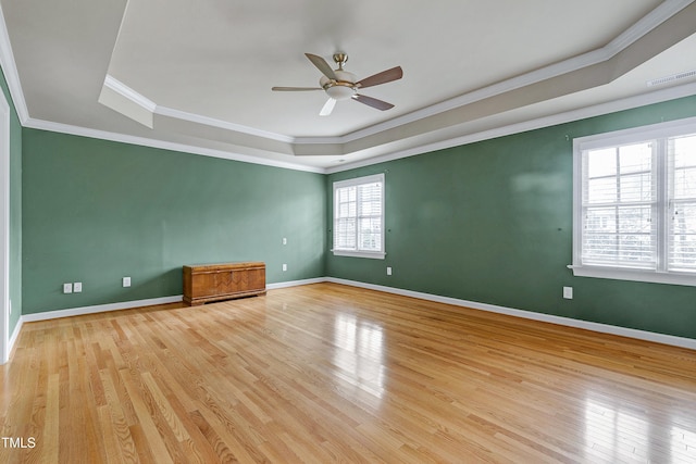 unfurnished room with a tray ceiling, wood finished floors, and visible vents