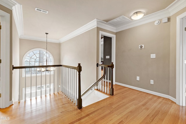 hall with wood finished floors, an upstairs landing, baseboards, visible vents, and an inviting chandelier