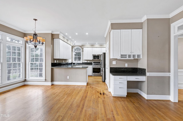 kitchen featuring white cabinets, dark countertops, light wood-style flooring, stainless steel appliances, and crown molding