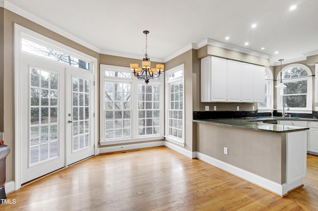 kitchen featuring white cabinets, crown molding, a peninsula, and light wood finished floors