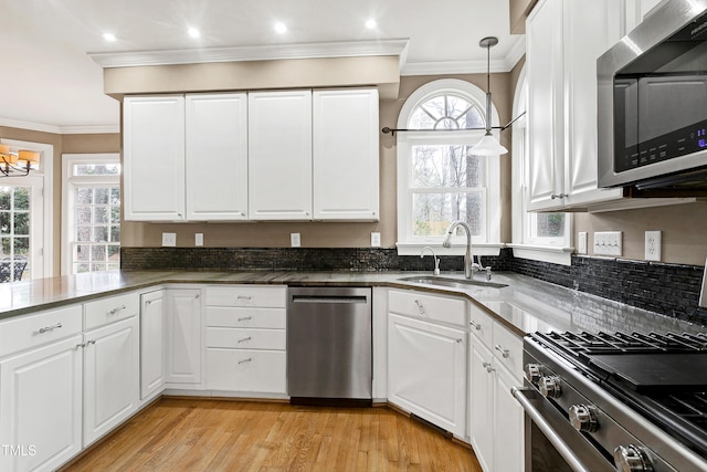 kitchen with stainless steel appliances, a sink, white cabinets, and crown molding