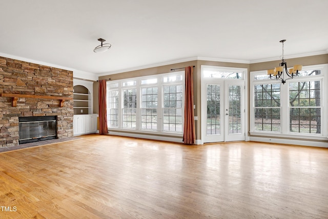 unfurnished living room with a wealth of natural light, wood finished floors, crown molding, and a stone fireplace