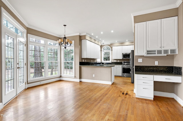 kitchen with dark countertops, appliances with stainless steel finishes, light wood-style floors, ornamental molding, and a sink