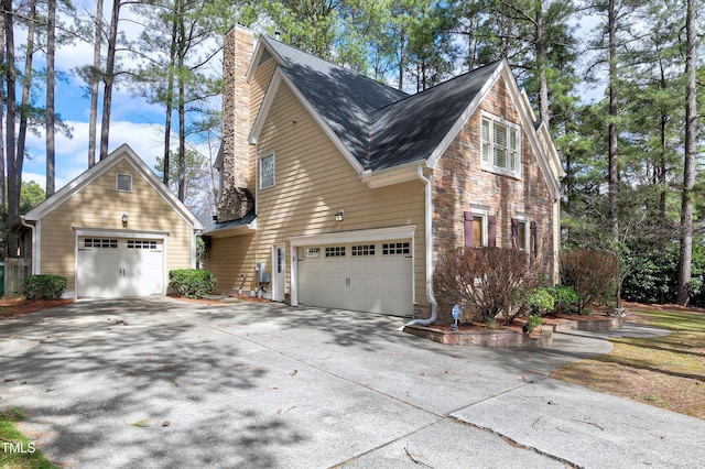 view of home's exterior with a garage, a shingled roof, stone siding, driveway, and a chimney