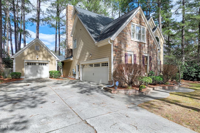 view of home's exterior featuring a garage, stone siding, concrete driveway, roof with shingles, and a chimney