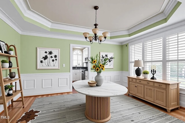 dining space with a chandelier, a raised ceiling, and light wood-type flooring