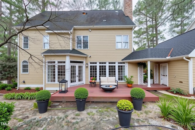 back of property with french doors, roof with shingles, a chimney, and a deck