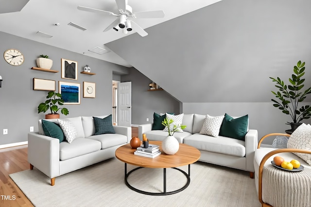 living area with ceiling fan, visible vents, vaulted ceiling, light wood-type flooring, and baseboards