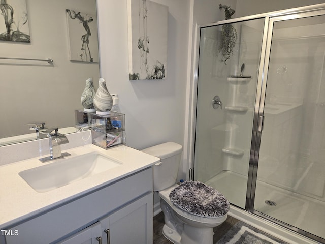 bathroom with vanity, a shower stall, and toilet