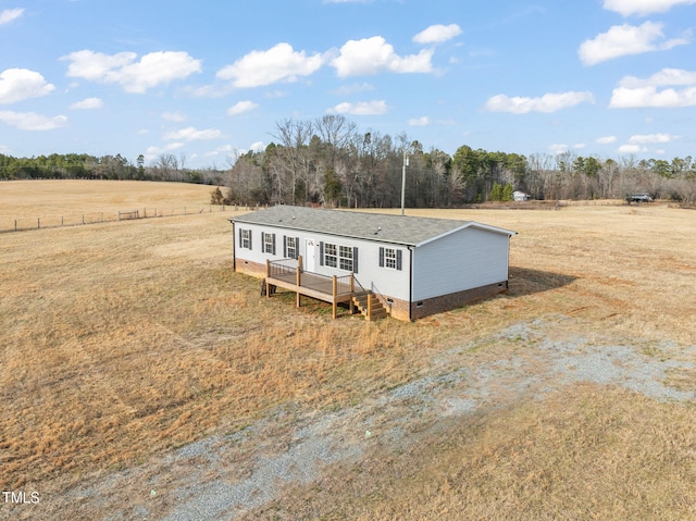 manufactured / mobile home with a wooden deck, a front lawn, and a rural view