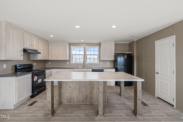 kitchen with a kitchen bar, sink, a center island, light wood-type flooring, and black appliances