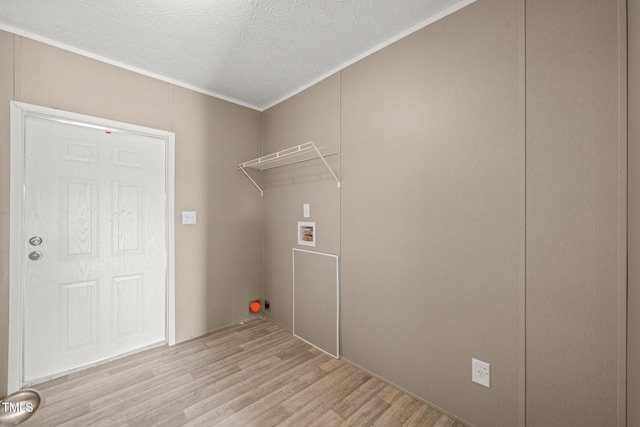 clothes washing area with ornamental molding, hookup for a washing machine, a textured ceiling, and light hardwood / wood-style flooring