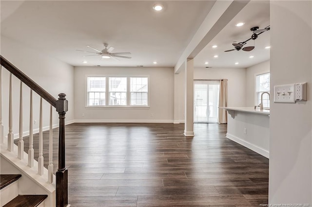 unfurnished living room featuring dark wood-type flooring and ceiling fan