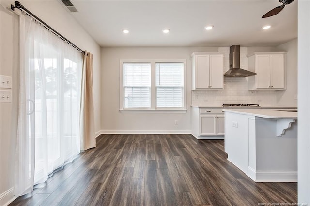 kitchen featuring backsplash, white cabinets, dark hardwood / wood-style floors, and wall chimney exhaust hood