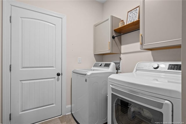 laundry room featuring washer and dryer and cabinets