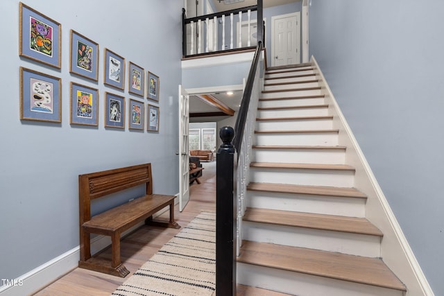 staircase featuring hardwood / wood-style floors and a high ceiling