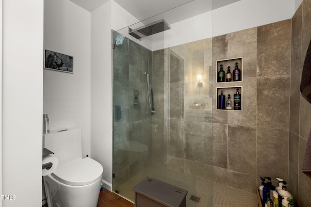 bathroom featuring a shower with door and toilet