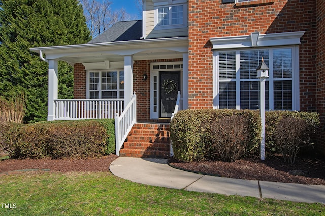 doorway to property with covered porch and brick siding