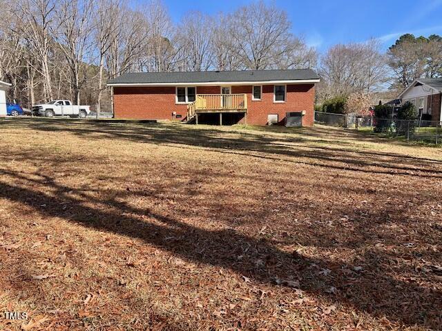 back of property with a deck and a lawn