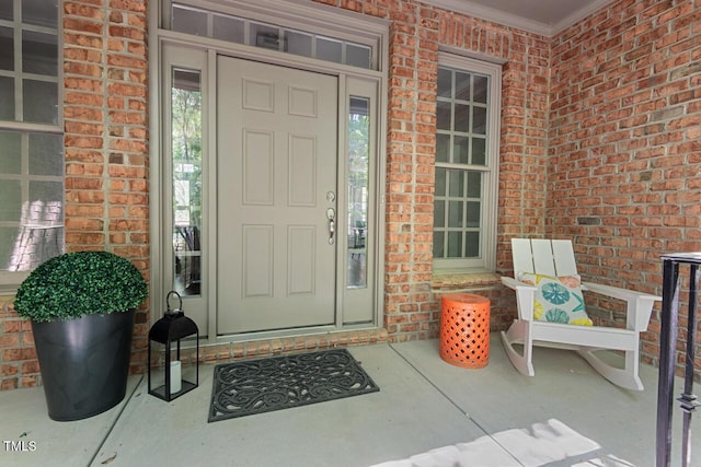 view of exterior entry featuring brick siding and a porch