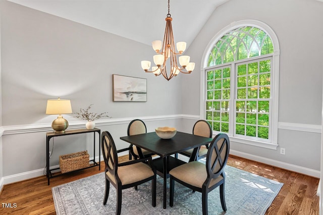 dining room with baseboards, an inviting chandelier, wood finished floors, and vaulted ceiling