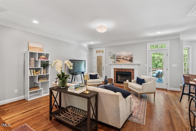living room with crown molding, baseboards, a fireplace, and wood finished floors