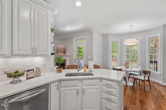 kitchen with dishwasher, a sink, light countertops, white cabinets, and a peninsula