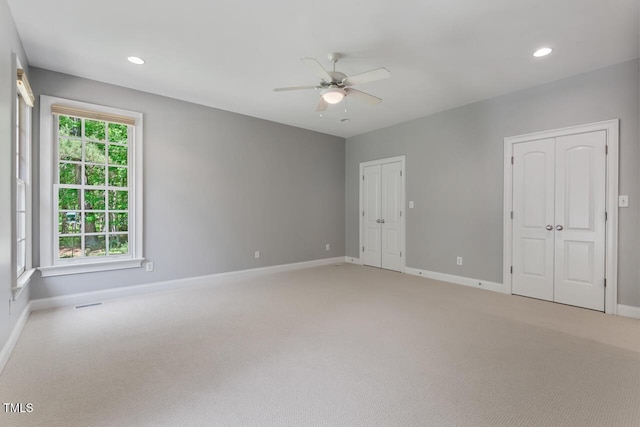 unfurnished bedroom with baseboards, recessed lighting, two closets, and light carpet
