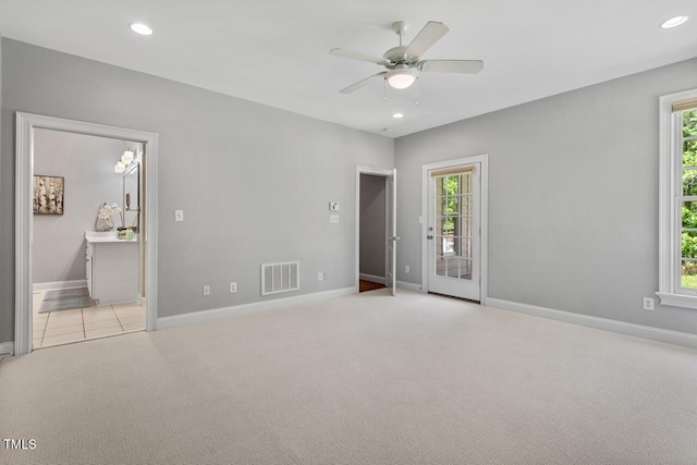 spare room featuring plenty of natural light, ceiling fan, carpet, and visible vents