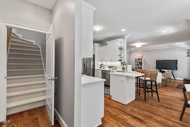 kitchen featuring white cabinets, open shelves, appliances with stainless steel finishes, light countertops, and a kitchen breakfast bar