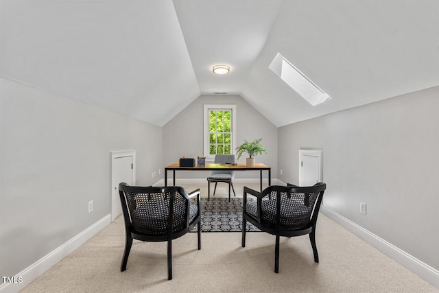 office featuring baseboards, lofted ceiling with skylight, and light colored carpet
