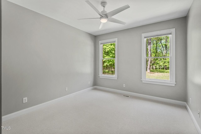 carpeted empty room with baseboards, ceiling fan, and a wealth of natural light
