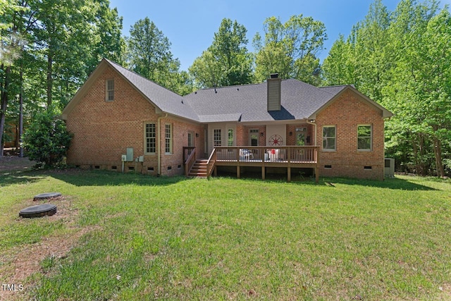 rear view of property featuring brick siding, a wooden deck, crawl space, a chimney, and a lawn