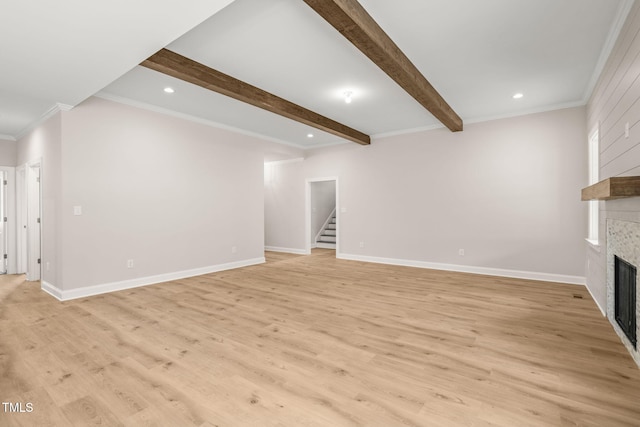 unfurnished living room featuring beam ceiling, a fireplace, light wood finished floors, stairway, and baseboards