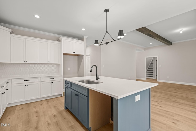 kitchen with tasteful backsplash, light wood-style floors, a sink, and white cabinets