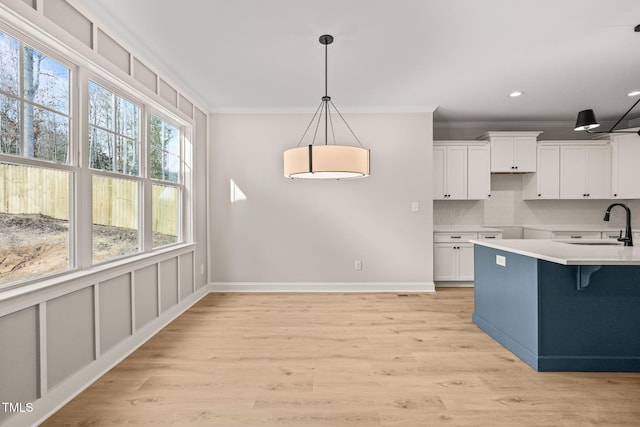 kitchen featuring crown molding, a sink, white cabinetry, backsplash, and pendant lighting