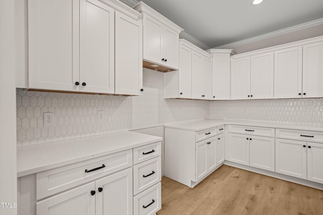 kitchen with white cabinetry, light wood-style floors, light countertops, ornamental molding, and decorative backsplash