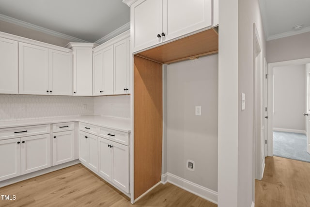 kitchen with crown molding, light countertops, decorative backsplash, light wood-style floors, and white cabinets