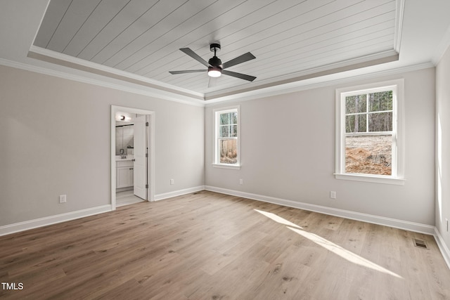 unfurnished bedroom featuring a tray ceiling, wood finished floors, visible vents, and crown molding