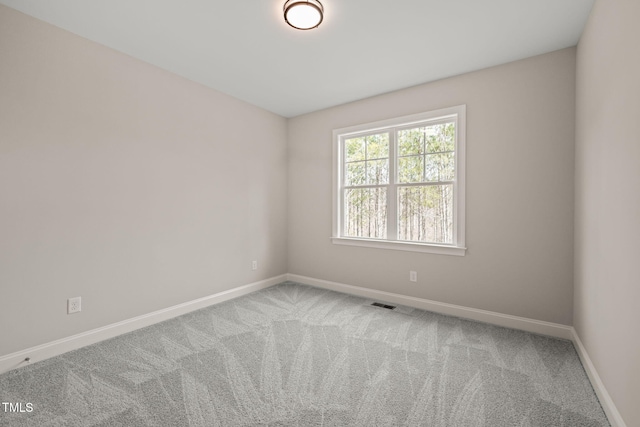 unfurnished room featuring carpet floors, visible vents, and baseboards