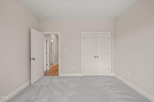 unfurnished bedroom with carpet, a closet, and baseboards