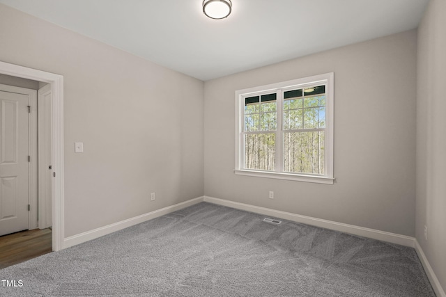 unfurnished room with carpet, visible vents, and baseboards