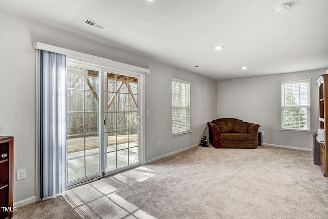 living area featuring light carpet, visible vents, and baseboards