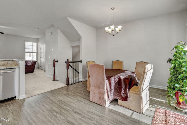 dining room with light wood-type flooring, an inviting chandelier, and baseboards