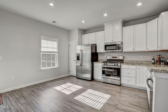 kitchen with light wood finished floors, baseboards, white cabinets, visible vents, and stainless steel appliances