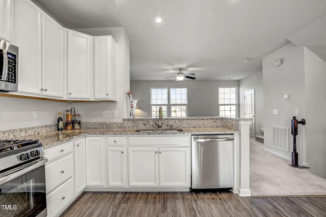 kitchen featuring white cabinets, light stone countertops, stainless steel appliances, and a sink