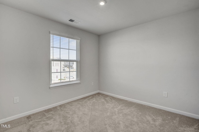 spare room featuring light carpet, visible vents, and baseboards