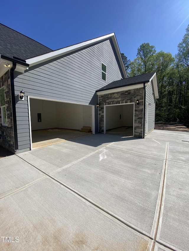 view of side of home featuring driveway and stone siding